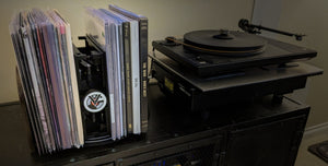 RecordStay among vinyl records beside a turntable, viewed at an angle.