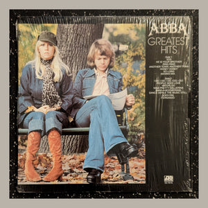 ABBA - Greatest Hits, actual copy, actual back: reader and seated woman; title column on right, complete physical edges visible in a matching light frame